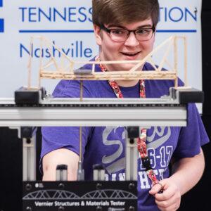 Student applies the load to his bridge during a competition