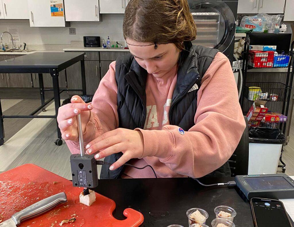 CTE Student using a Vernier Dual Range Force sensor to test meat tenderness.