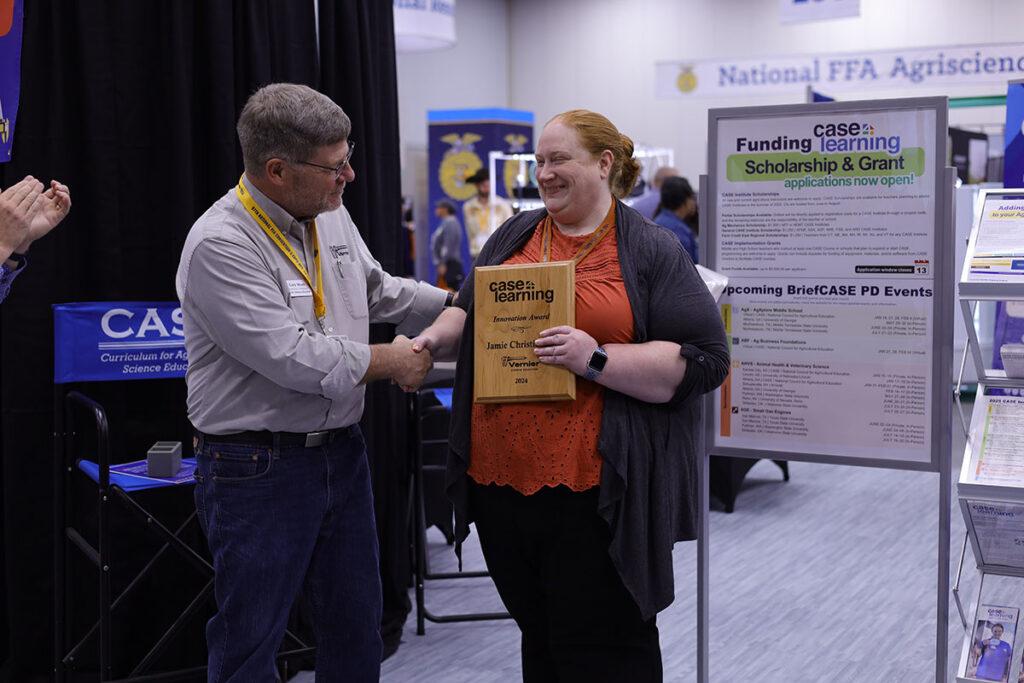 CASE 2024 Awardee: Jamie Christiansen, sponsored by Vernier Science Education. Jamie holding her award in her left hand, Gary Myers shaking her other hand.