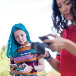 Students match motion graphs displayed on their smartphones by moving forward and backward parallel to a school building wall